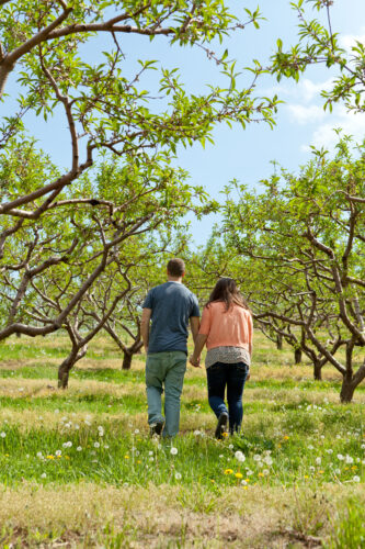 young happy couple enjoying each others company outdoors through a country apple orchard rF2Nb90ro