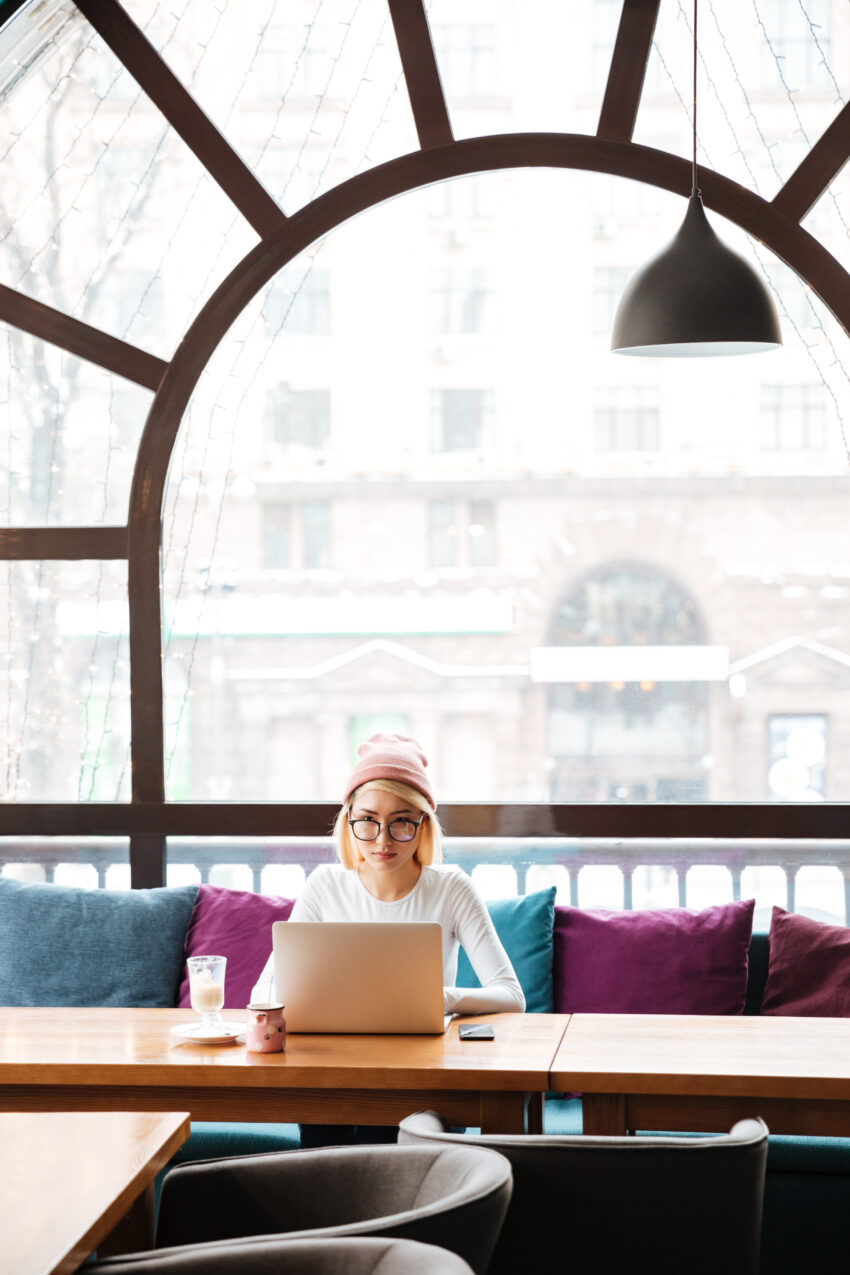 graphicstock concentrated young woman in hat and glasses working with laptop in cafe BkWgKO0pe