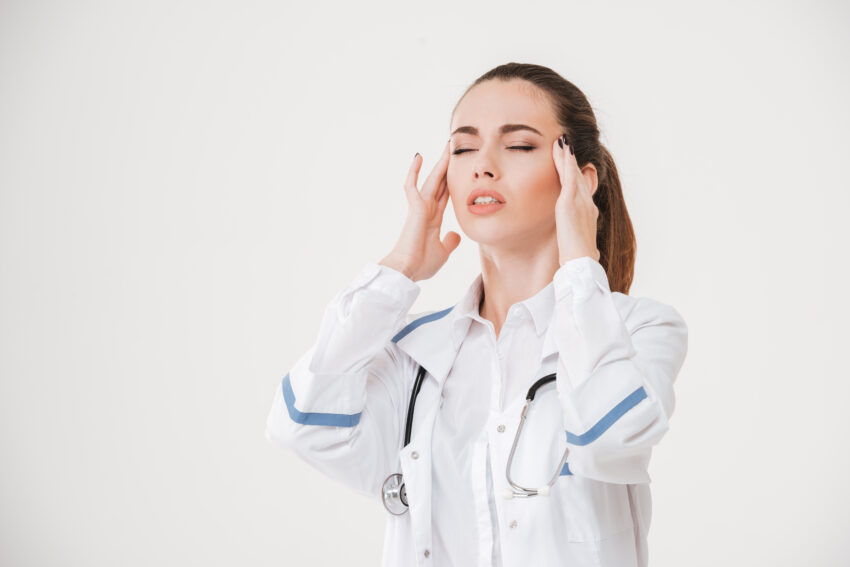 graphicstock depressed young woman doctor touching her temples and having headache over white background SO rtlJw2g