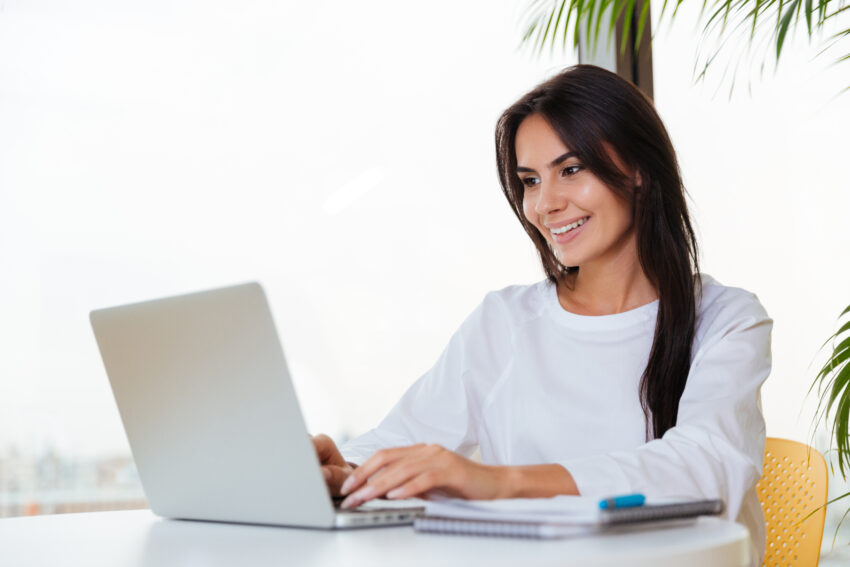 graphicstock happy pretty young businesswoman smiling and using laptop in office rUG9svQdhe