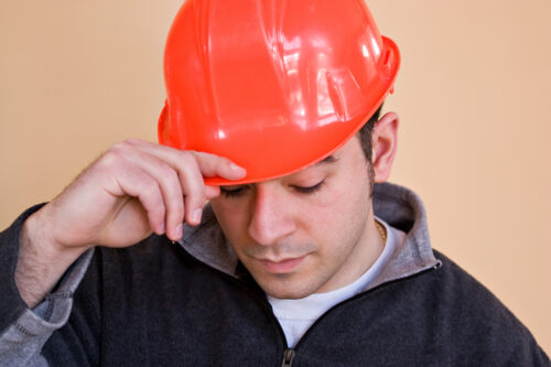 a young construction professional tips putting on his hard hat BFURYDRSi 1