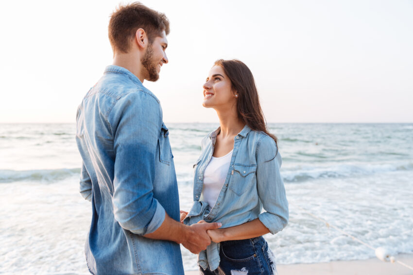 graphicstock happy young couple in love standing and holding hands on the beach B xL CcH2e